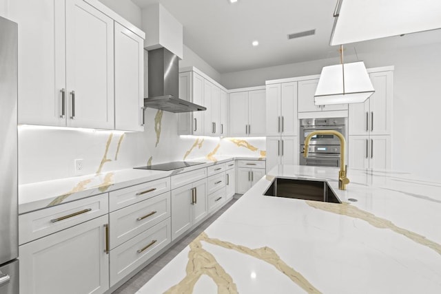 kitchen with black electric cooktop, double oven, light stone counters, and white cabinets