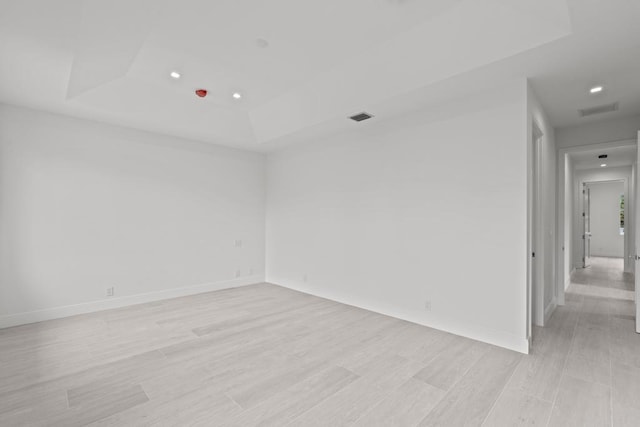 spare room featuring a raised ceiling and light hardwood / wood-style floors