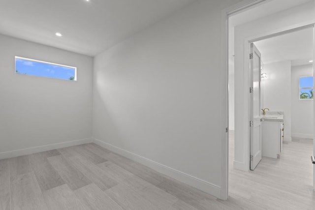 spare room featuring sink, light hardwood / wood-style flooring, and a healthy amount of sunlight