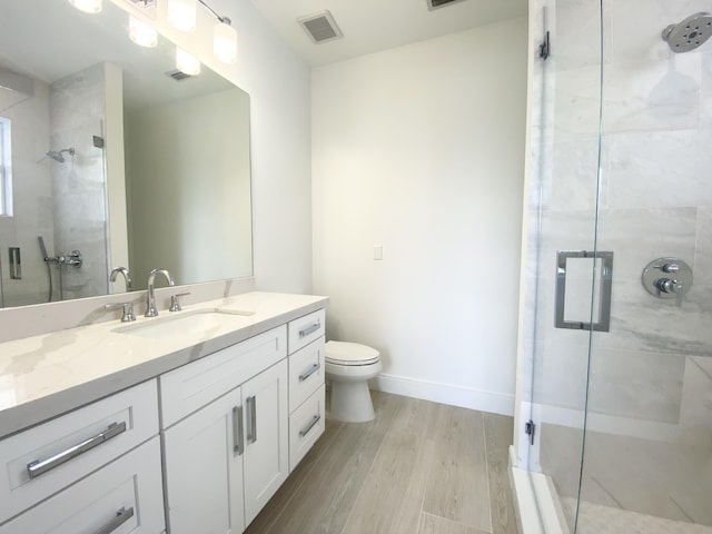 bathroom with an enclosed shower, vanity, hardwood / wood-style flooring, and toilet