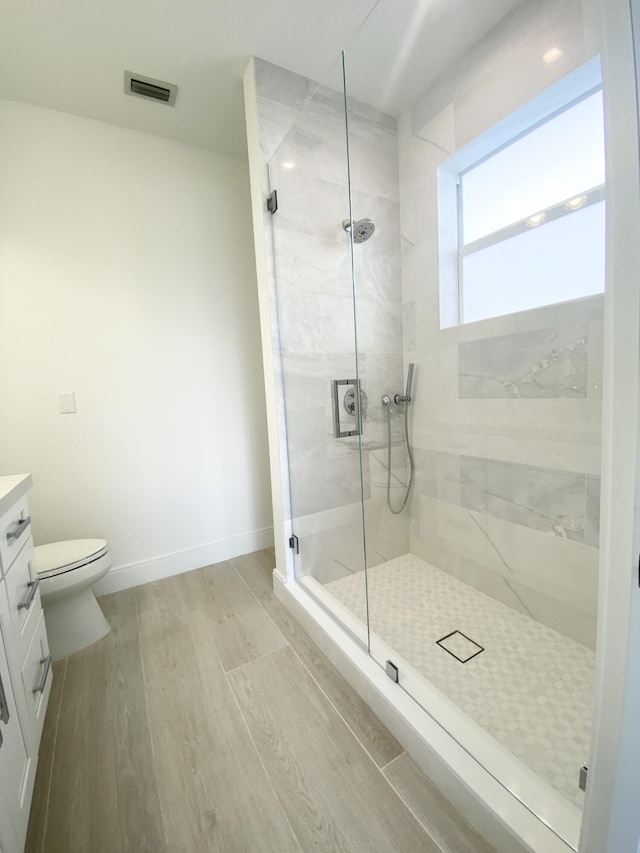 bathroom with vanity, hardwood / wood-style flooring, a shower with shower door, and toilet