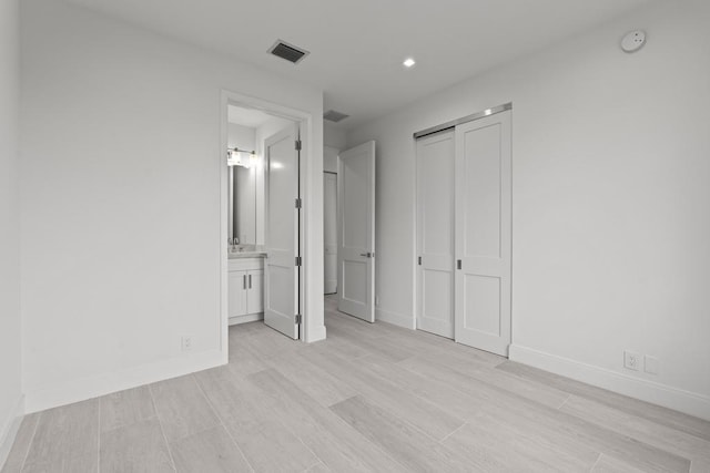 unfurnished bedroom with light hardwood / wood-style floors, a closet, and ensuite bathroom