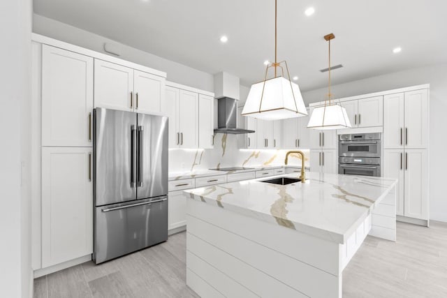 kitchen featuring appliances with stainless steel finishes, sink, white cabinets, hanging light fixtures, and a center island with sink