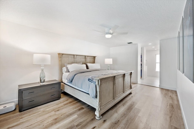 bedroom featuring a textured ceiling, ceiling fan, and light hardwood / wood-style flooring