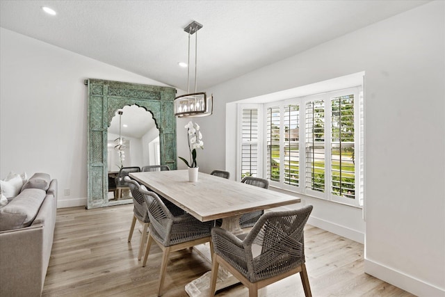 dining space featuring a notable chandelier, vaulted ceiling, and light wood-type flooring