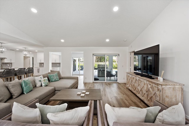 living room with lofted ceiling, light hardwood / wood-style flooring, and a textured ceiling