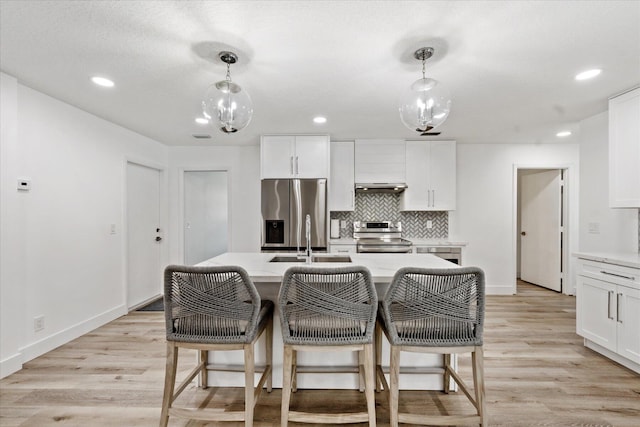 kitchen featuring white cabinetry, appliances with stainless steel finishes, sink, and decorative light fixtures