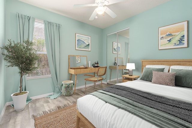 bedroom featuring a closet, baseboards, wood finished floors, and a ceiling fan