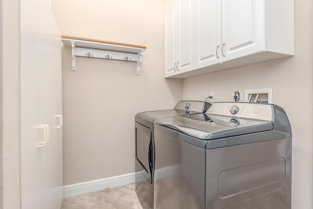 clothes washing area with washer and dryer, baseboards, and cabinet space