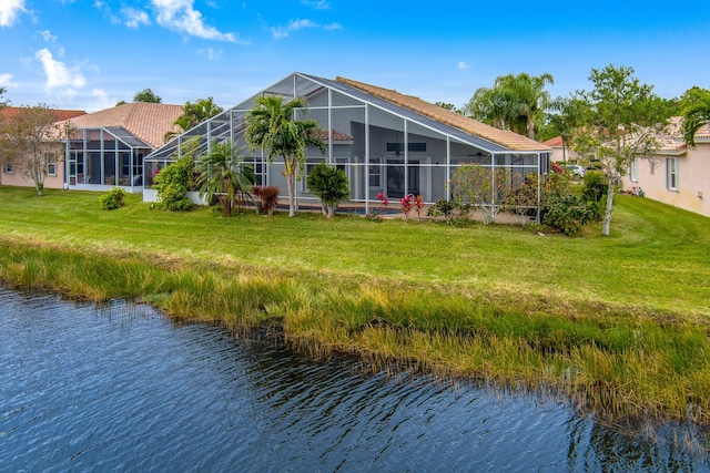 back of house with a lanai, a lawn, and a water view