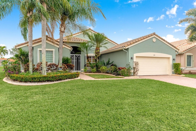 mediterranean / spanish-style home featuring stucco siding, decorative driveway, a front yard, a garage, and a tiled roof