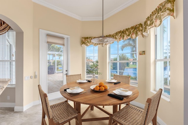 dining space featuring baseboards, arched walkways, and ornamental molding