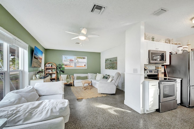 living room with ceiling fan and a textured ceiling