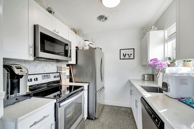 kitchen with appliances with stainless steel finishes, white cabinetry, sink, backsplash, and a textured ceiling