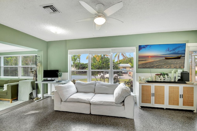 living room with ceiling fan and a textured ceiling