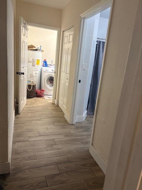 hallway with washer / clothes dryer, hardwood / wood-style flooring, and water heater