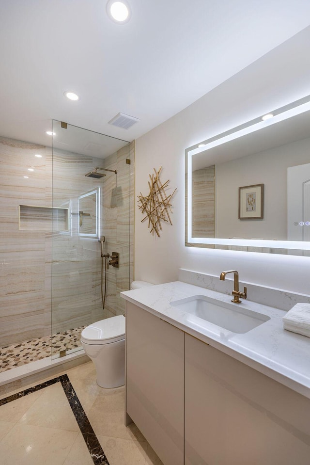 bathroom with vanity, toilet, and a tile shower