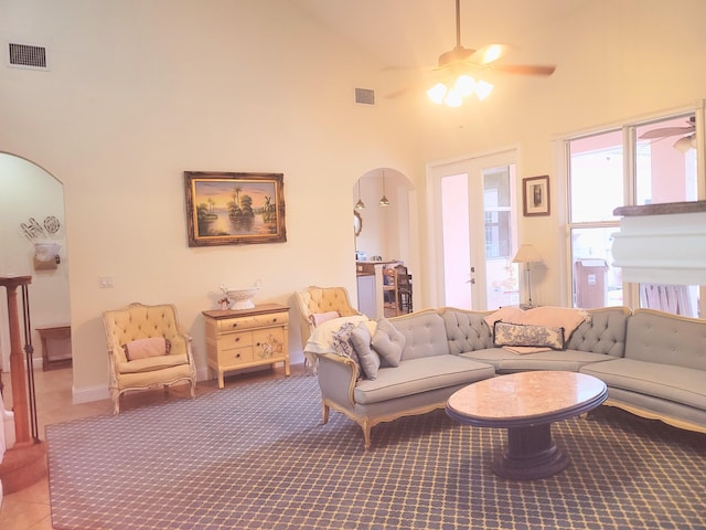 living room featuring arched walkways, visible vents, a high ceiling, and ceiling fan