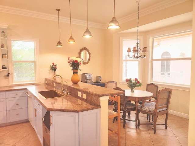 kitchen with a peninsula, plenty of natural light, crown molding, and a sink