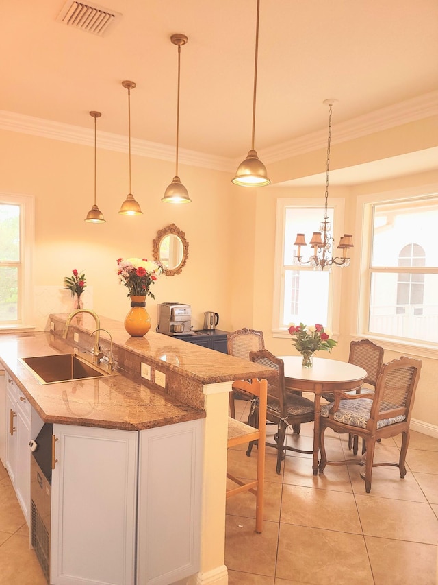 kitchen featuring visible vents, white cabinets, crown molding, and a sink