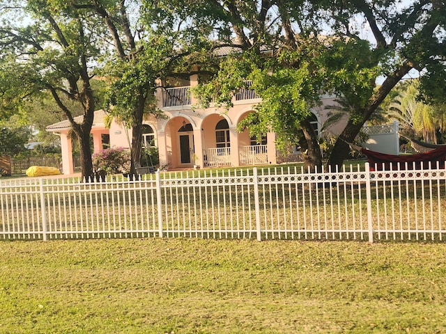 view of front facade featuring a front yard, a balcony, a fenced front yard, and stucco siding