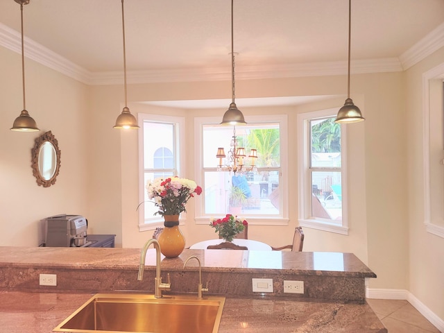 kitchen with tile patterned floors, pendant lighting, a sink, crown molding, and stone counters