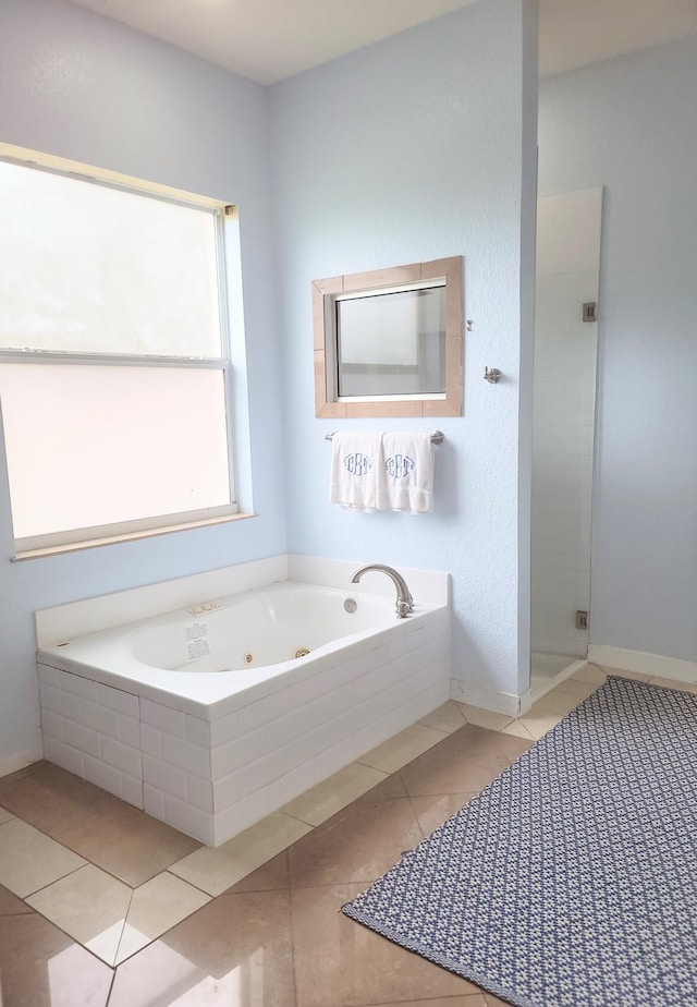 full bathroom with tile patterned floors, a tub with jets, baseboards, and a shower stall