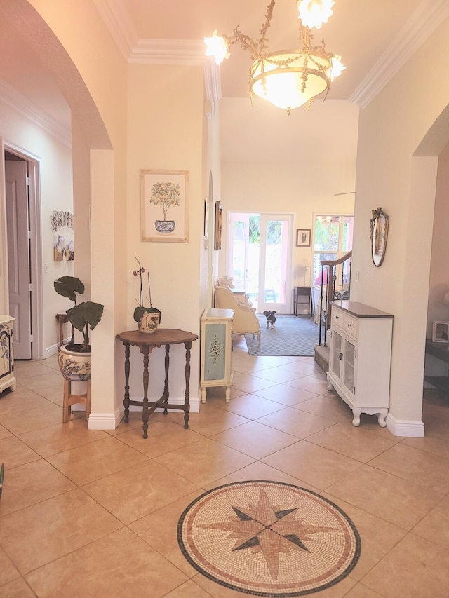 hall featuring light tile patterned floors, baseboards, arched walkways, ornamental molding, and a towering ceiling