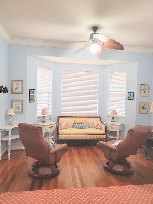 living area with a healthy amount of sunlight, wood finished floors, ceiling fan, and ornamental molding