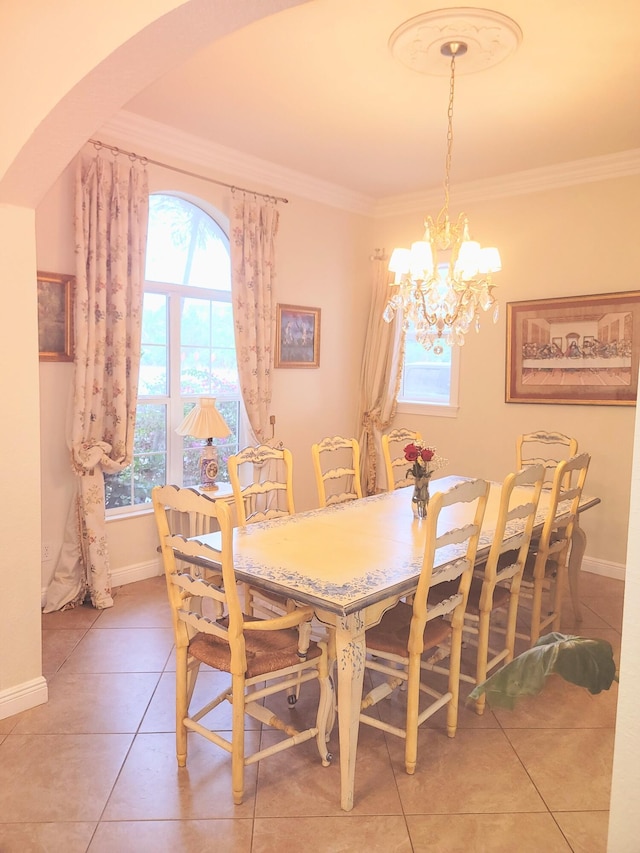 dining space with crown molding, a notable chandelier, arched walkways, and light tile patterned floors