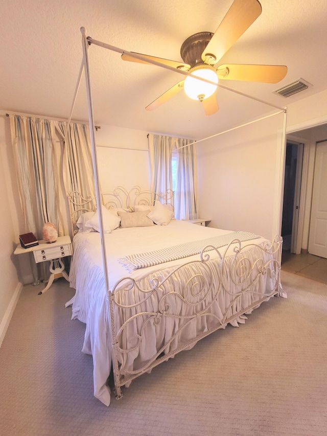 bedroom featuring a ceiling fan, carpet, visible vents, and a textured ceiling