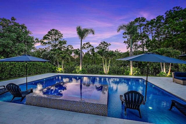 pool at dusk featuring a patio area, an outdoor pool, and a hot tub