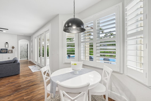 dining room with arched walkways and wood finished floors