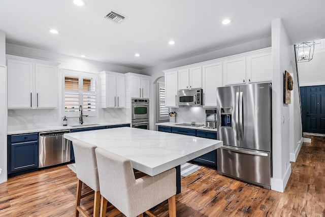 kitchen featuring a kitchen island, a breakfast bar, white cabinetry, sink, and stainless steel appliances