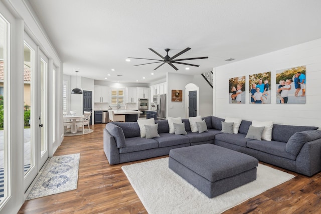 living area with arched walkways, dark wood-style floors, recessed lighting, and visible vents