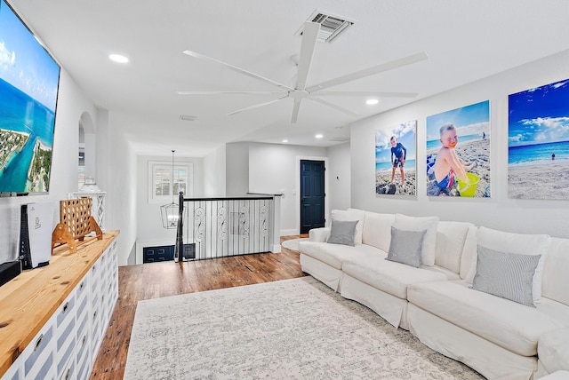 living area with visible vents, recessed lighting, wood finished floors, arched walkways, and a ceiling fan