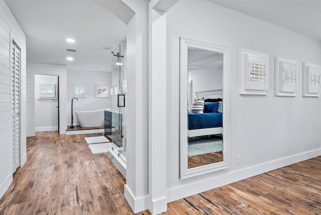 corridor with arched walkways, baseboards, and wood finished floors