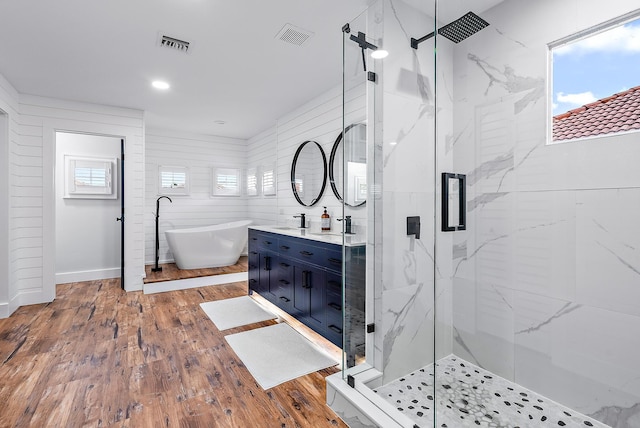 bathroom with a soaking tub, wood finished floors, visible vents, and a marble finish shower