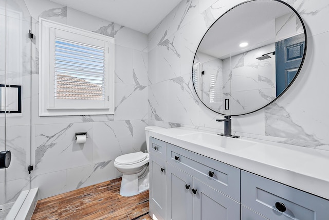 bathroom featuring tile walls, hardwood / wood-style flooring, vanity, walk in shower, and toilet