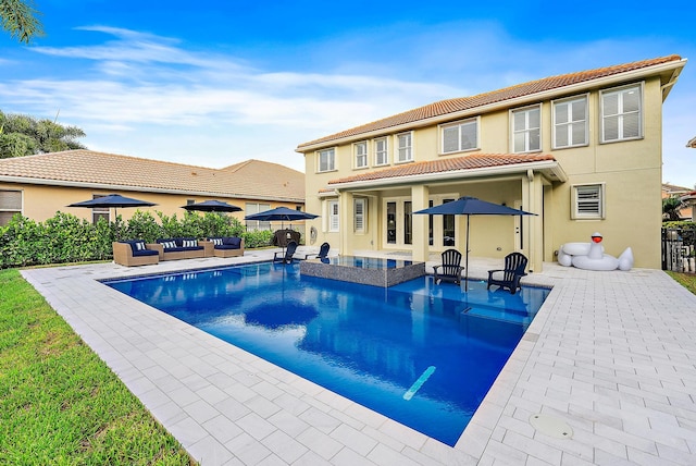 back of house with an outdoor living space, a patio, a pool with hot tub, and french doors