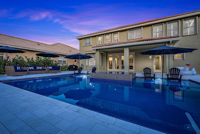 pool at dusk featuring an outdoor hangout area and a patio area