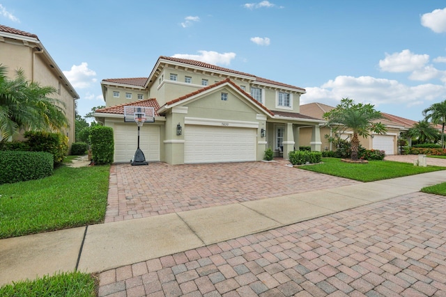 view of front of house with a tiled roof, a front yard, stucco siding, decorative driveway, and a garage