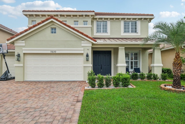 view of front of home with a front yard, covered porch, stucco siding, decorative driveway, and a garage