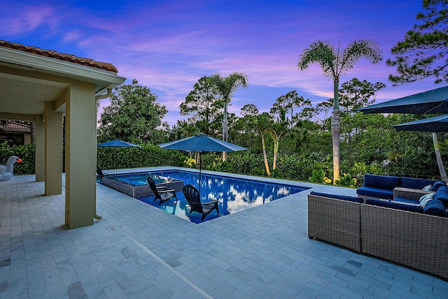 pool at dusk with an outdoor hangout area, a jacuzzi, and a patio area