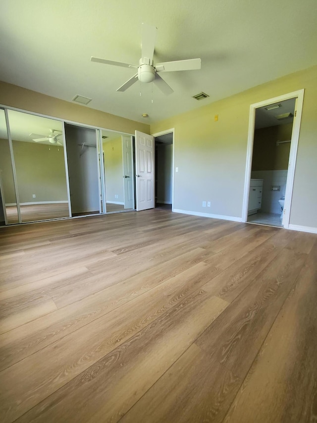 unfurnished bedroom with visible vents, multiple closets, baseboards, and wood finished floors