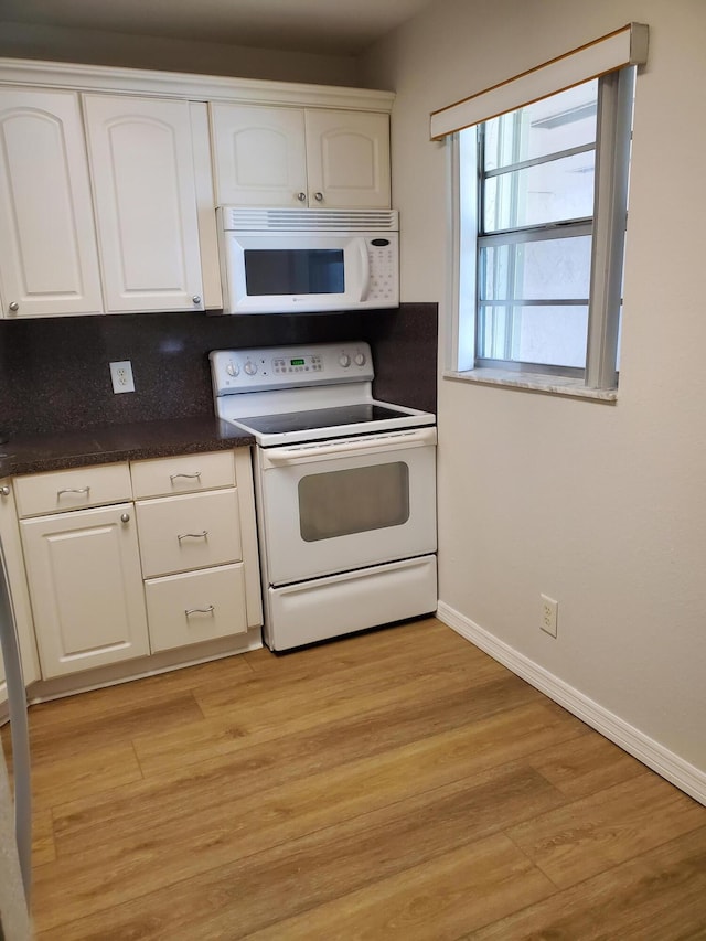 kitchen with light wood-style floors, white appliances, dark countertops, and white cabinets