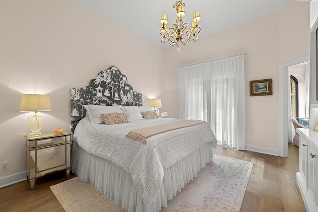 bedroom with light wood finished floors, an inviting chandelier, and baseboards