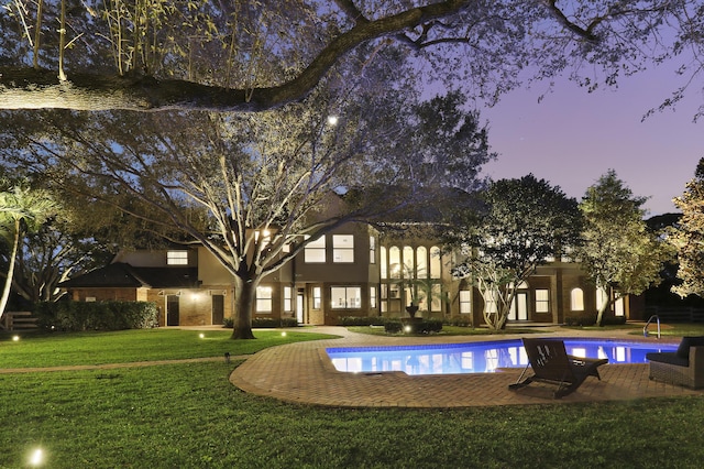 pool at dusk featuring a yard