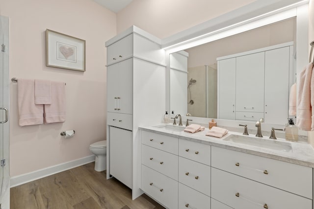 full bathroom with a sink, double vanity, wood finished floors, and a shower stall