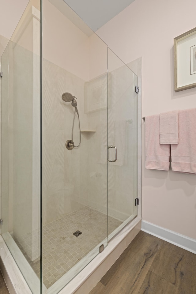 bathroom featuring baseboards, wood finished floors, and a shower stall